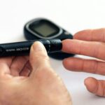 Close-up image of a person using a glucometer for diabetes management indoors.