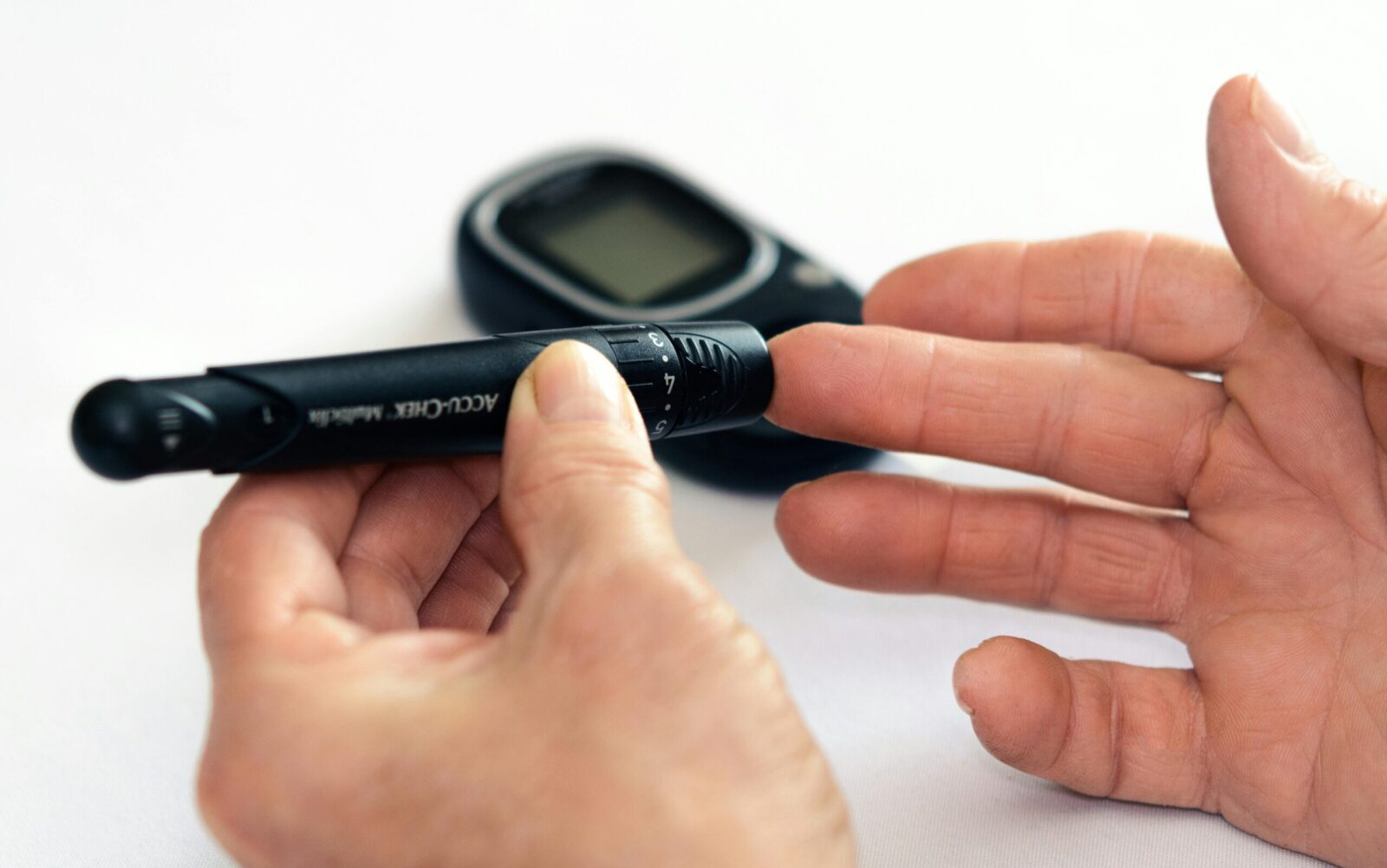 Close-up image of a person using a glucometer for diabetes management indoors.