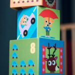 A child playing indoors, stacking colorful wooden toy blocks with joyful illustrations.